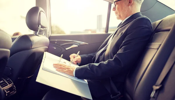 Hombre de negocios senior con papeles conduciendo en coche —  Fotos de Stock