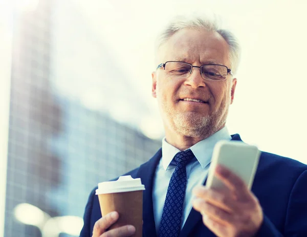 Бизнесмен со смартфоном и кофе в городе — стоковое фото