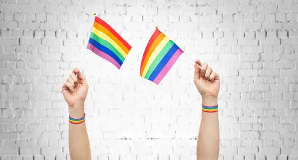 Τα χέρια με την γκέι υπερηφάνεια ουράνιο τόξο σημαίες και βραχιολάκια — Φωτογραφία Αρχείου
