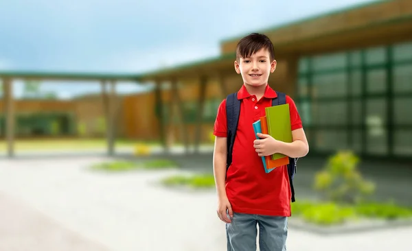 Lächelnder Schüler mit Büchern und Schultasche — Stockfoto