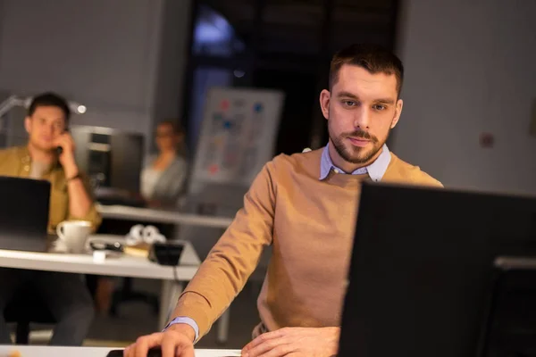 Человек с компьютером работает допоздна в ночном офисе — стоковое фото