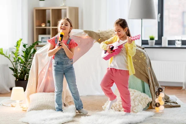 Meninas com guitarra e microfone jogando em casa — Fotografia de Stock