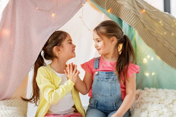 Szczęśliwy dziewcząt leżący w namiot dzieci i rozmowa w Dom — Zdjęcie stockowe