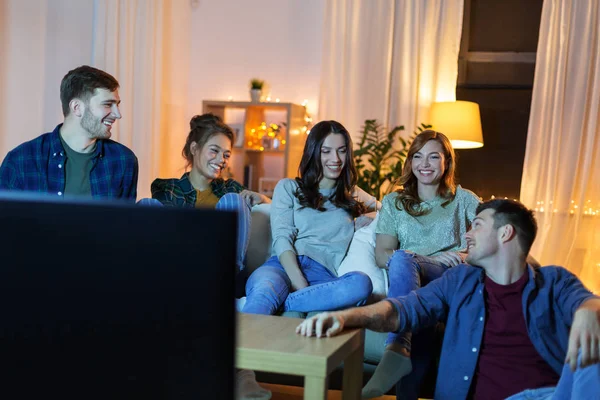 Amici felici guardando la tv a casa la sera — Foto Stock
