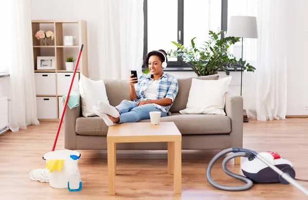 Mujer en auriculares descansando después de la limpieza del hogar —  Fotos de Stock