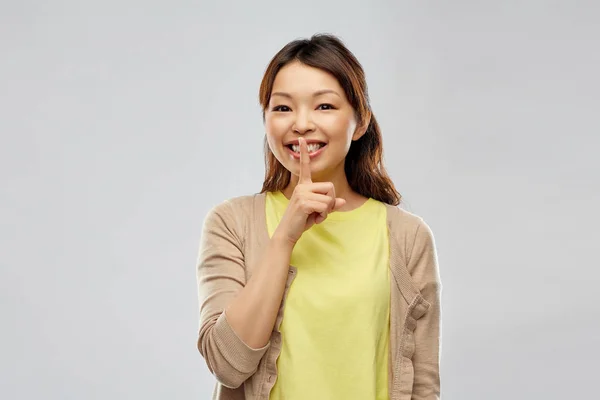 Glücklich asiatische Frau mit Finger auf Lippen — Stockfoto