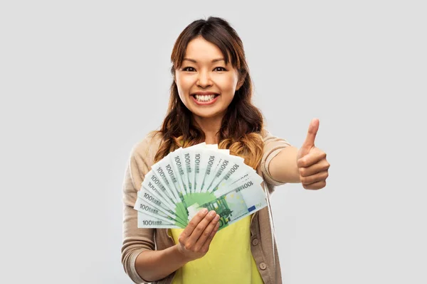 Mujer asiática con euro dinero mostrando pulgares arriba — Foto de Stock