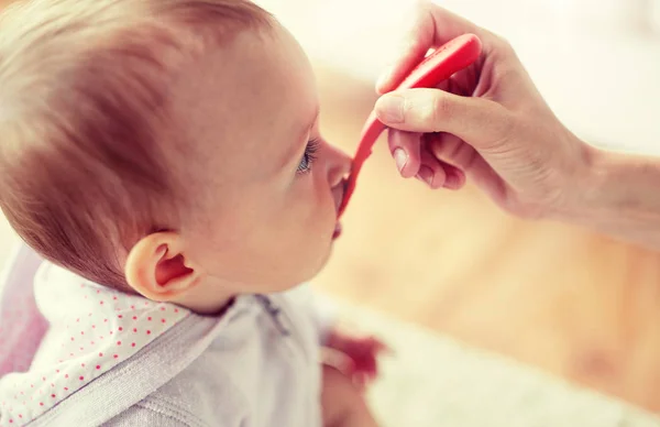 Hand mit Löffel füttert kleines Baby zu Hause — Stockfoto