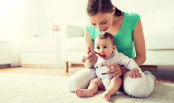 Mother with spoon feeding little baby at home — Stock Photo, Image