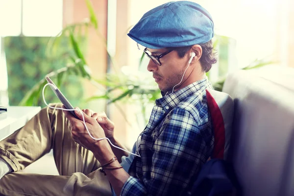 Hombre con tablet PC y auriculares sentados en la cafetería —  Fotos de Stock