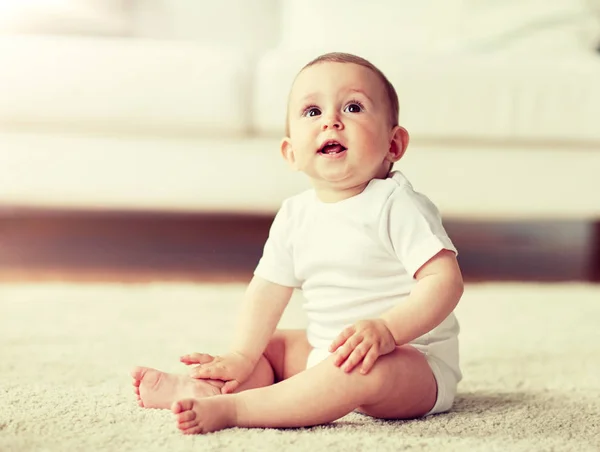 Glücklicher kleiner Junge oder Mädchen, die zu Hause auf dem Boden sitzen — Stockfoto