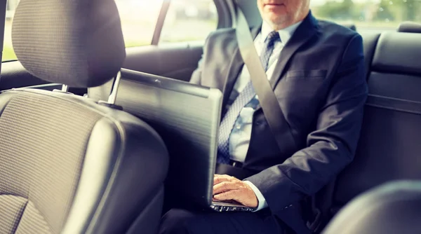 Empresário sênior com laptop dirigindo no carro — Fotografia de Stock