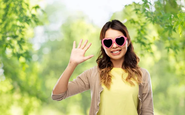 Mujer asiática en gafas de sol en forma de corazón agitando la mano — Foto de Stock