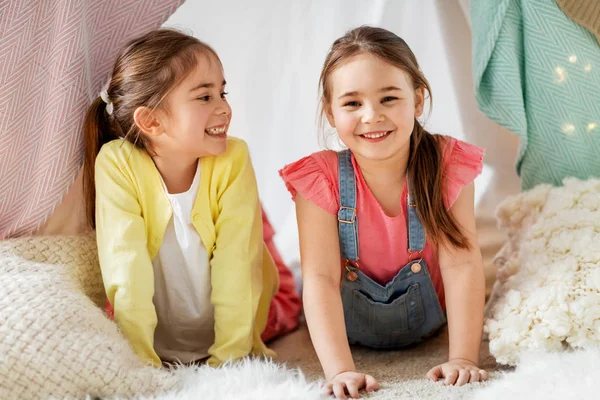 Happy girls lying in kids tent at home — Stock Photo, Image