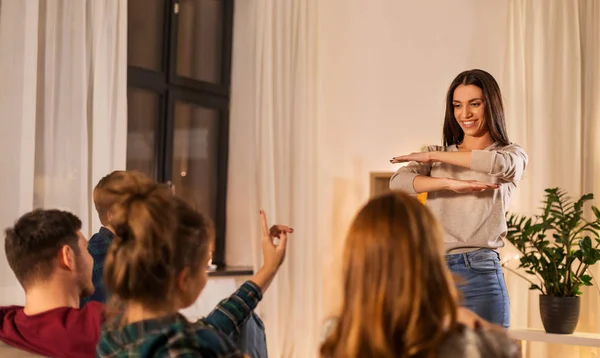 Happy friends playing charades at home in evening — Stock Photo, Image