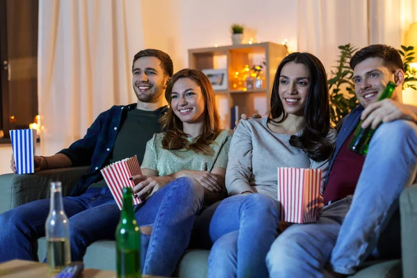 Přátelé s pivem a popcorn sledování televize doma — Stock fotografie
