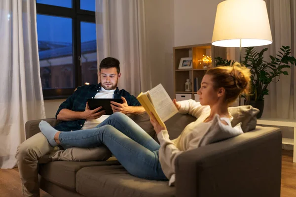 Casal com computador tablet e livro em casa — Fotografia de Stock