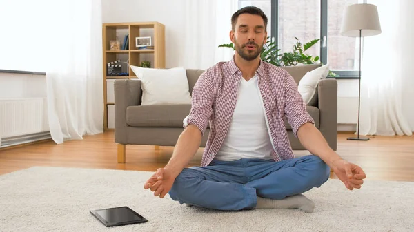 Hombre con tablet ordenador meditando en casa —  Fotos de Stock