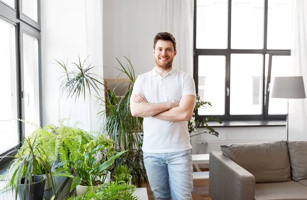 Усміхнений чоловік з кімнатними рослинами вдома — стокове фото
