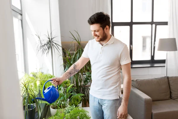 Mann gießt Zimmerpflanzen zu Hause — Stockfoto