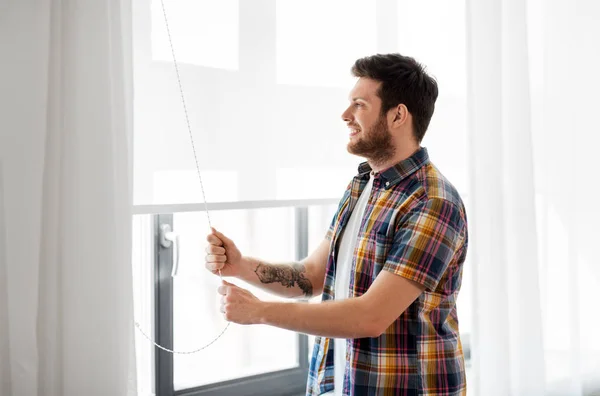 Mann öffnet Rollladen an Fenster zu Hause — Stockfoto