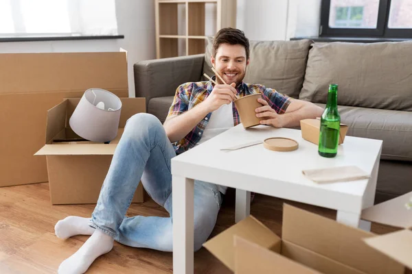 Lächelnder Mann isst im neuen Zuhause Essen zum Mitnehmen — Stockfoto