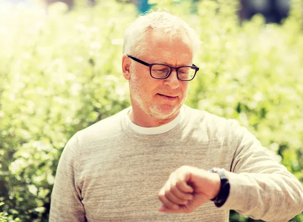 Senior man controleert de tijd op zijn polshorloge — Stockfoto