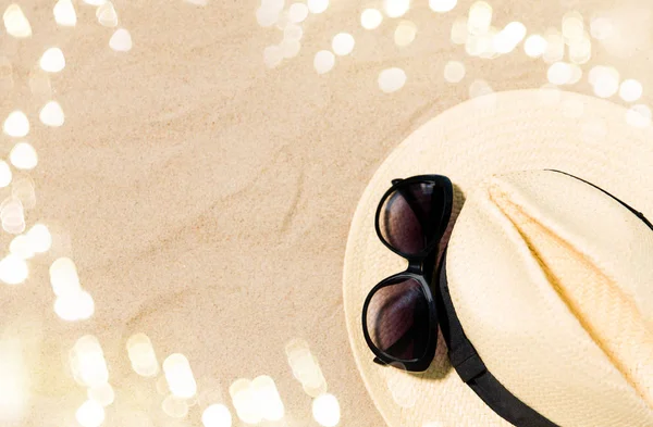 Chapéu de palha e óculos de sol na areia da praia — Fotografia de Stock
