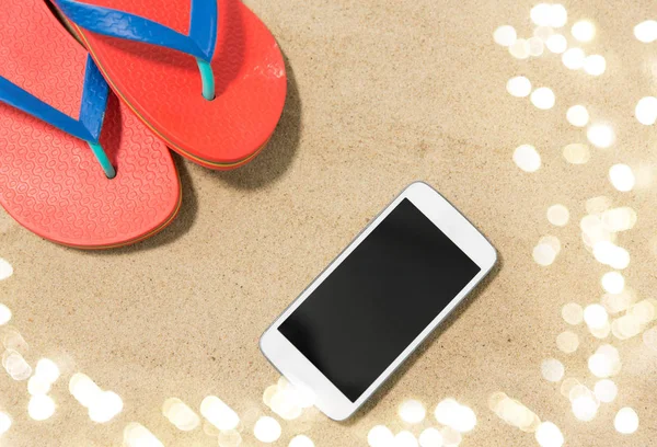 Smartphone i klapki japonki na plaży piasek — Zdjęcie stockowe
