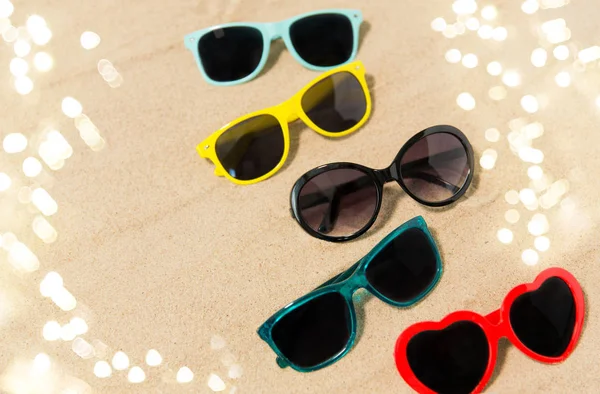 Different sunglasses on beach sand — Stock Photo, Image