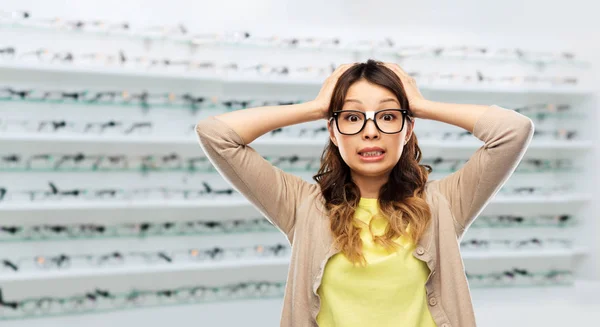 Žena v brýlích drží hlavu v obchodě s optikou — Stock fotografie