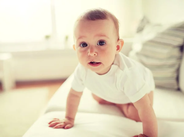 Pequeno bebê em fralda rastejando ao longo do sofá em casa — Fotografia de Stock