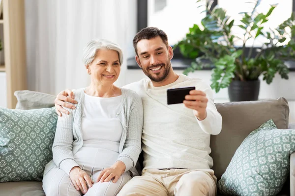 Senior mother with adult son taking selfie at home — Stock Photo, Image