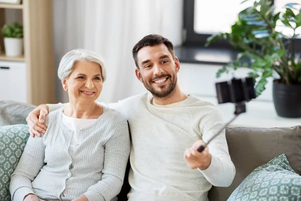 Madre anziana con figlio adulto che prende selfie a casa — Foto Stock