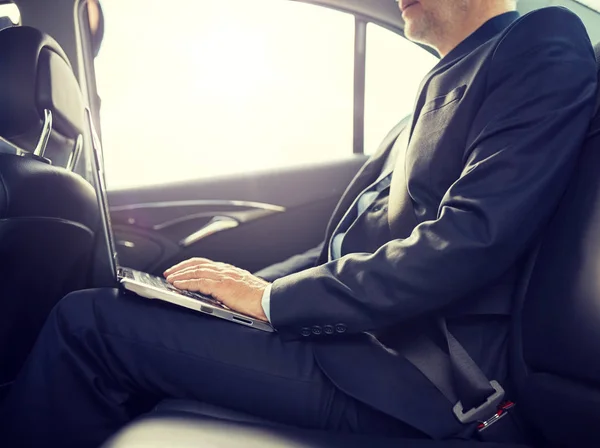 Empresário sênior com laptop dirigindo no carro — Fotografia de Stock