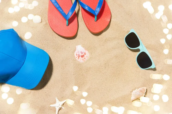 Cap, flip flops, shades and on shells beach sand — Stock Photo, Image