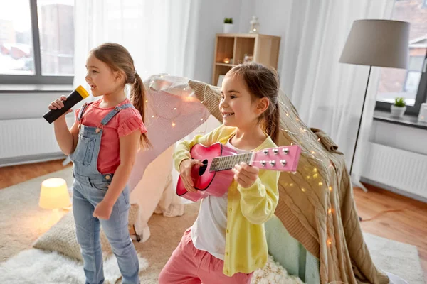 Meninas com guitarra e microfone jogando em casa — Fotografia de Stock