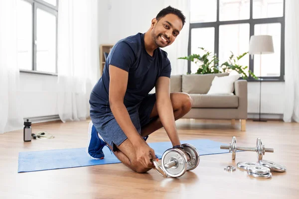 Sorridente indiana homem montando halteres em casa — Fotografia de Stock