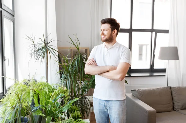 Lächelnder Mann mit Zimmerpflanzen zu Hause — Stockfoto