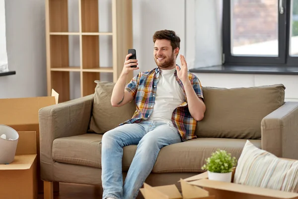 Hombre con teléfono inteligente que tiene videollamada en casa nueva —  Fotos de Stock