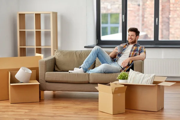 Hombre con cajas y beber café en casa nueva —  Fotos de Stock