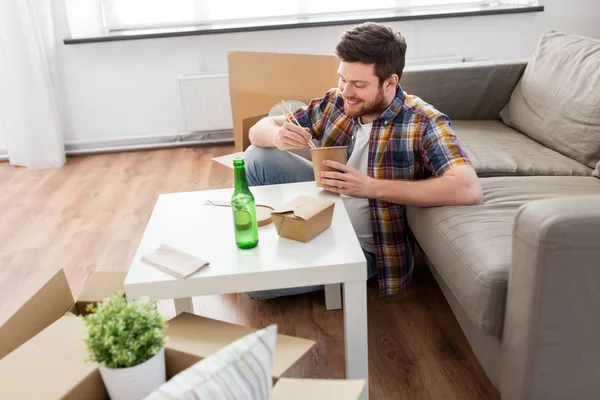 Leende man äter hämtmat i nytt hem — Stockfoto