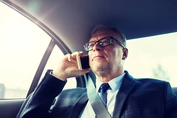 Starszy biznesmen dzwoni na smartfona w samochodzie — Zdjęcie stockowe