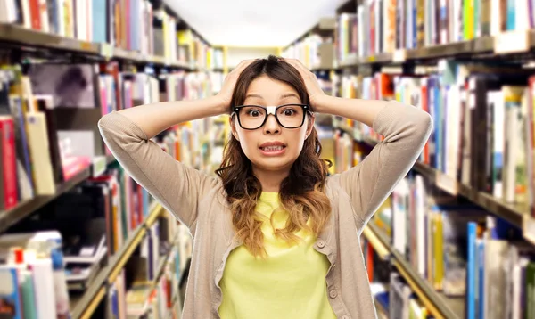 Asian female student holding to head at library — Stock Photo, Image