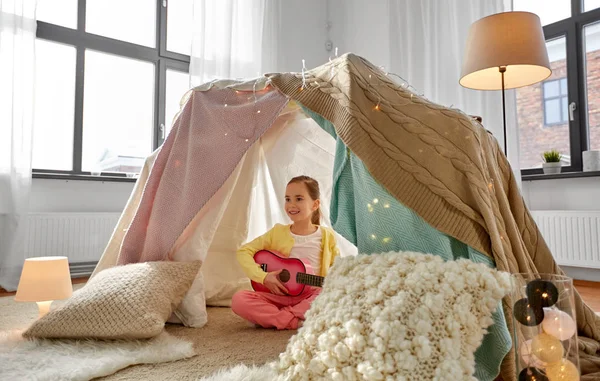 Petite fille jouant de la guitare dans une tente pour enfants à la maison — Photo