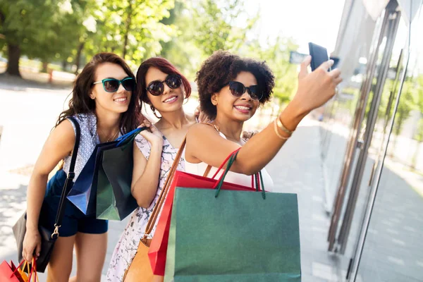 Femmes avec des sacs à provisions prenant selfie en ville — Photo