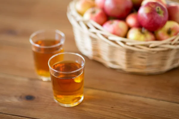 Manzanas en cesta y vasos de jugo en la mesa —  Fotos de Stock