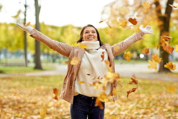 Happy woman having fun with leaves in autumn park — Stock Photo, Image