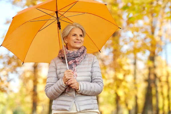 Wanita senior yang bahagia dengan payung di taman musim gugur — Stok Foto