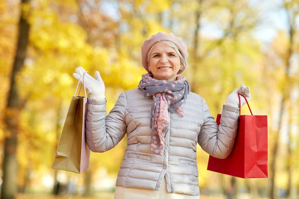 가을 공원에서 쇼핑백을 들고 있는 나이든 여자 — 스톡 사진